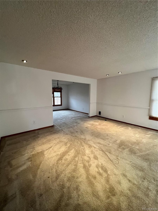 carpeted empty room featuring baseboards and a textured ceiling