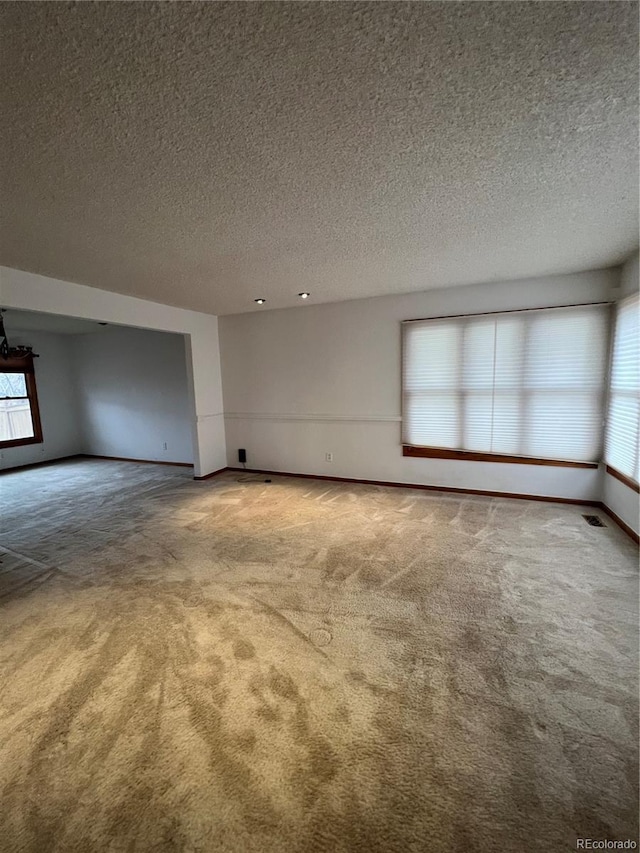 interior space featuring carpet, visible vents, baseboards, and a textured ceiling