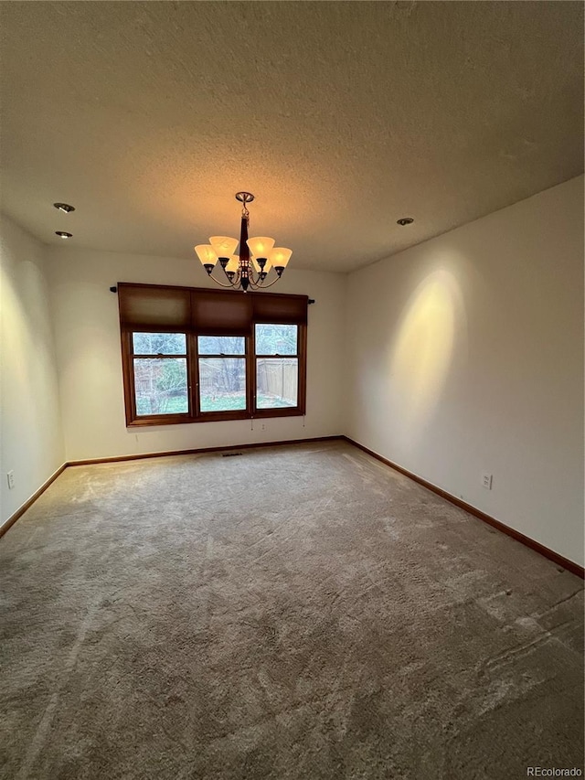 carpeted spare room featuring baseboards, a notable chandelier, and a textured ceiling