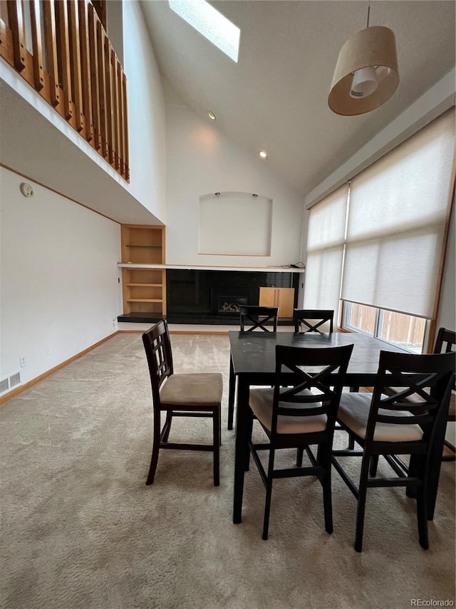 carpeted dining area featuring visible vents, a skylight, high vaulted ceiling, and baseboards