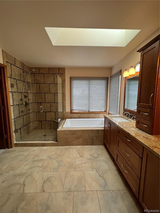 bathroom with a bath, a skylight, vanity, and a stall shower
