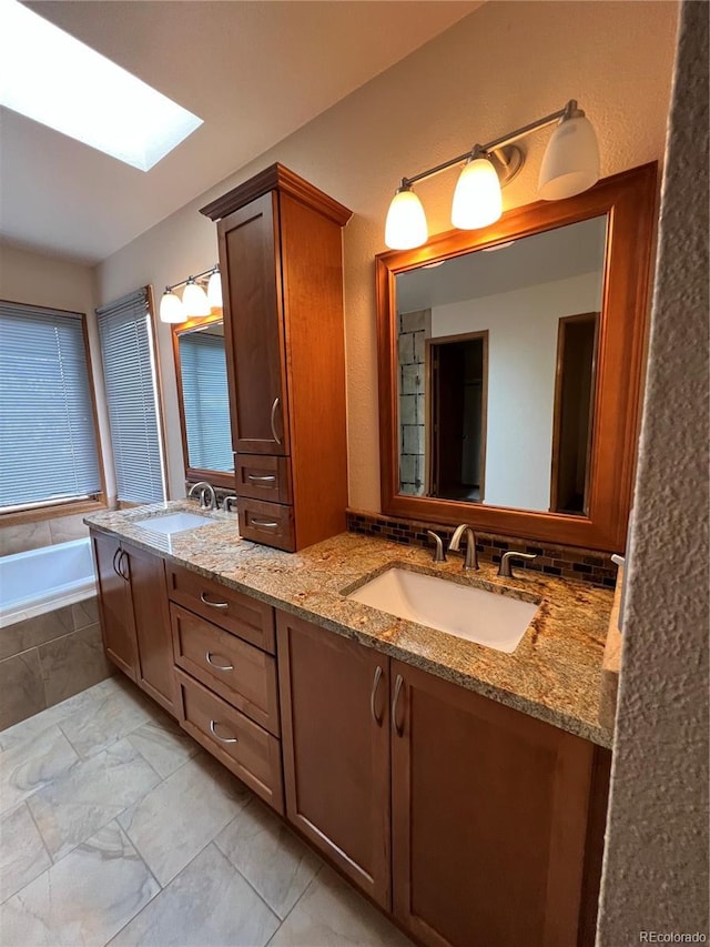 full bathroom with double vanity, a garden tub, a sink, and a skylight