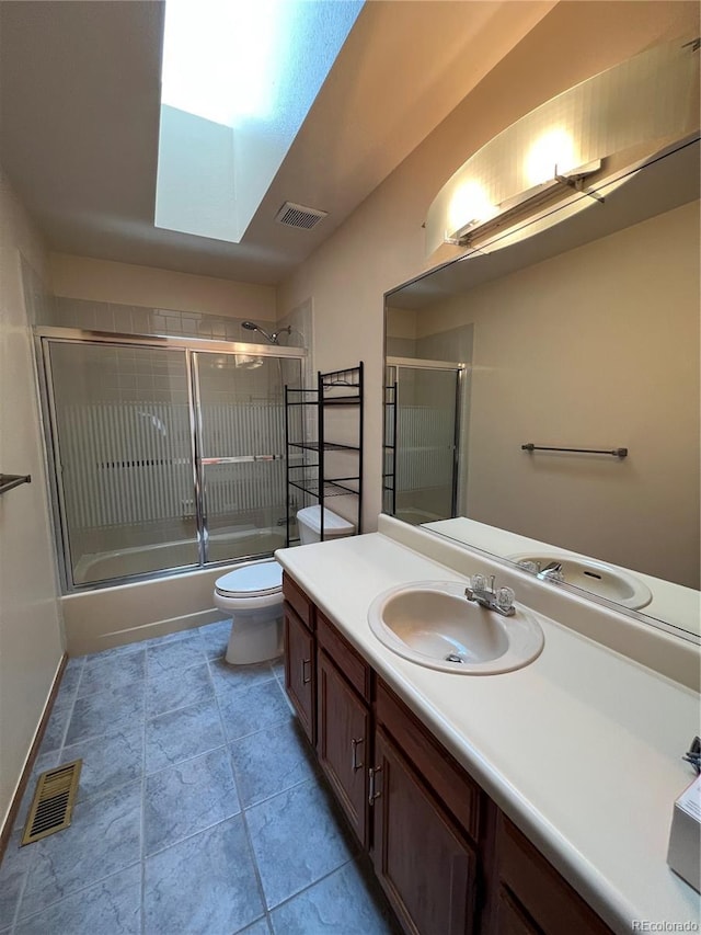 full bath with toilet, vanity, combined bath / shower with glass door, and visible vents