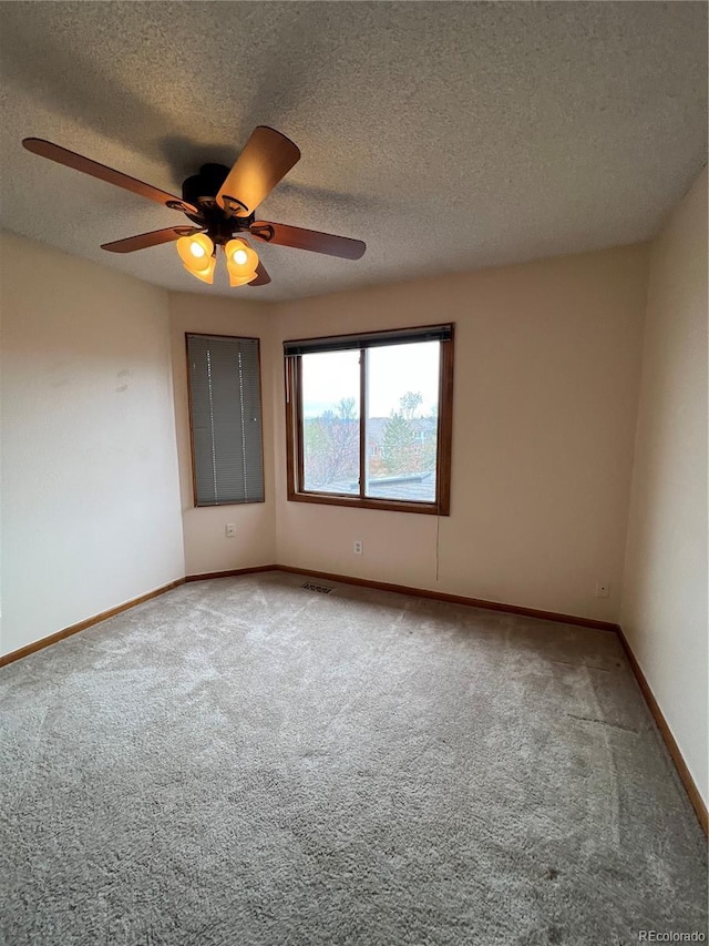 empty room featuring visible vents, carpet floors, baseboards, and ceiling fan