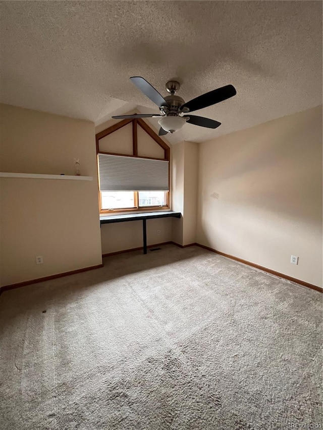 spare room featuring baseboards, a textured ceiling, a ceiling fan, carpet floors, and lofted ceiling