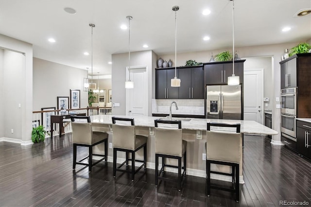22310 E Chenango Dr, Aurora, CO 80015 - kitchen featuring stainless steel appliances, a sink, backsplash, a spacious island, and dark wood-type flooring