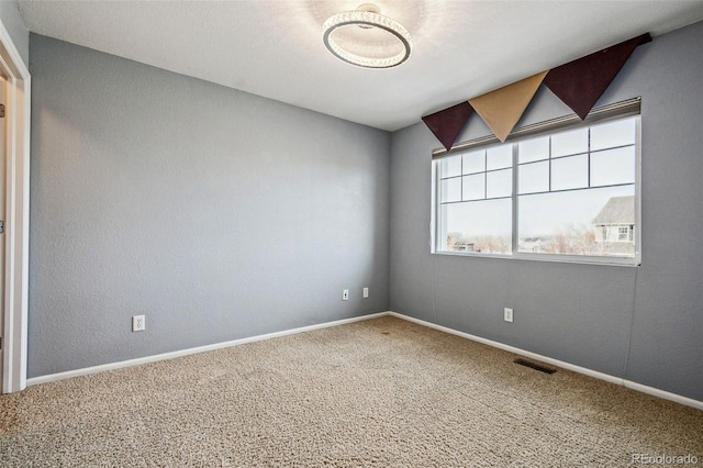 empty room with baseboards, visible vents, and carpet flooring