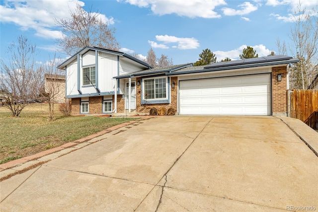 split level home featuring solar panels, fence, concrete driveway, and brick siding