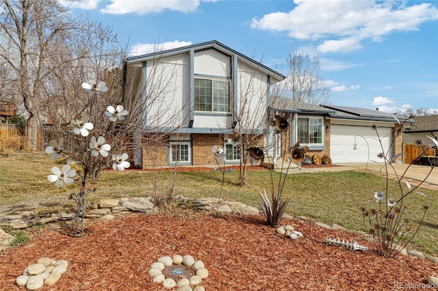 tri-level home with a garage, solar panels, brick siding, driveway, and a front yard