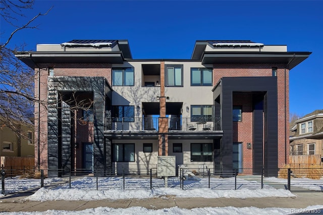 view of front of home featuring brick siding, fence, and stucco siding