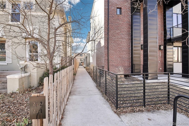 view of side of home featuring brick siding and fence