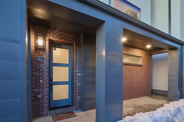 view of exterior entry with a garage and brick siding