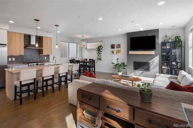 living area with dark wood-type flooring, a glass covered fireplace, baseboards, and recessed lighting