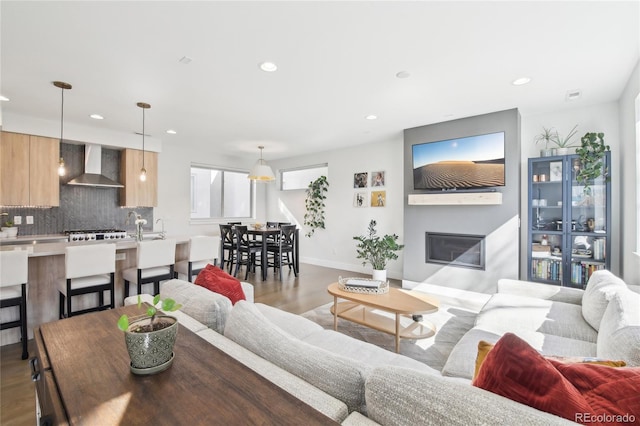 living room with recessed lighting, baseboards, wood finished floors, and a glass covered fireplace