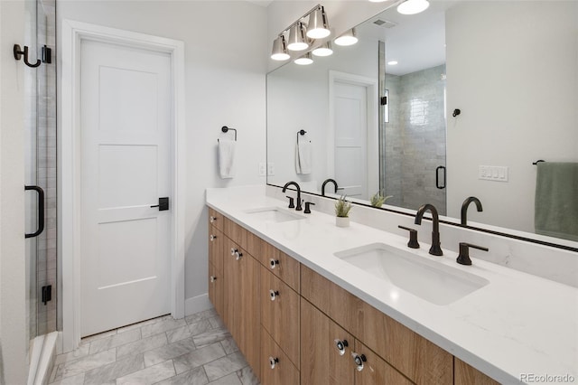 full bath featuring marble finish floor, tiled shower, and a sink