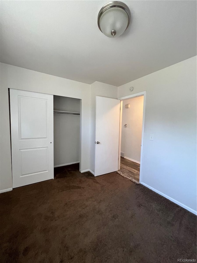 unfurnished bedroom featuring a closet and dark colored carpet