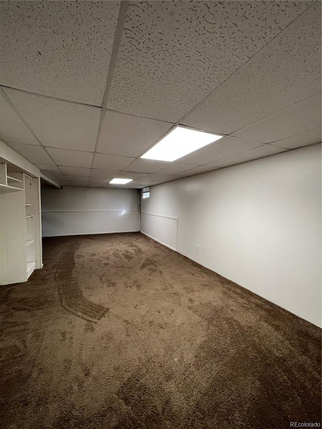 basement with a drop ceiling and dark carpet