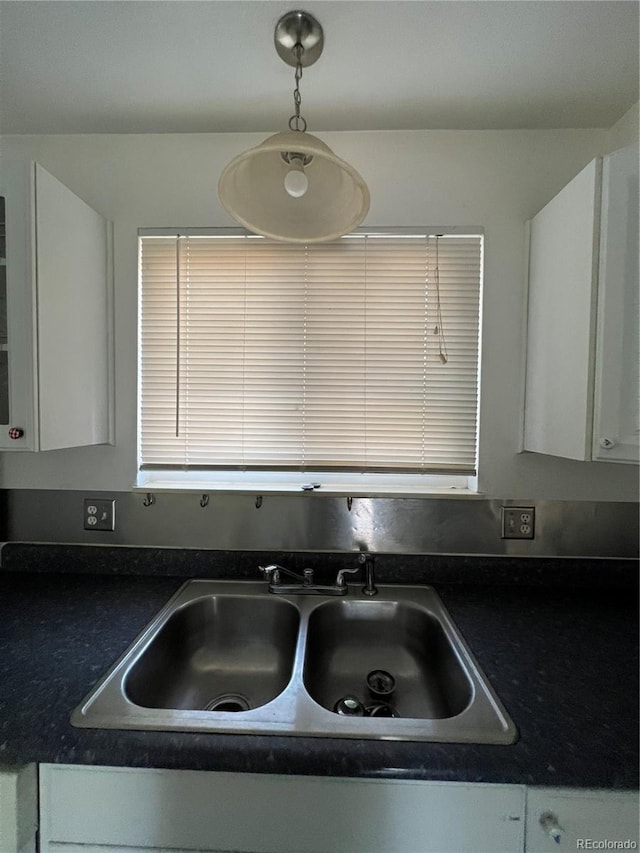 interior details with white cabinets, sink, and decorative light fixtures