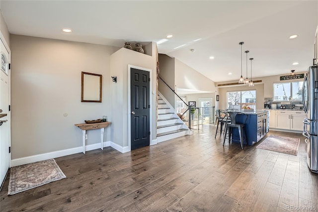 interior space featuring dark hardwood / wood-style flooring, white cabinets, a kitchen island, hanging light fixtures, and a breakfast bar area