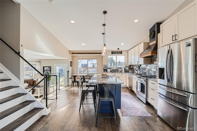 kitchen with a center island, decorative backsplash, light stone counters, white cabinetry, and stainless steel appliances