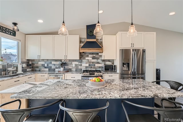 kitchen featuring sink, a center island, vaulted ceiling, a breakfast bar area, and appliances with stainless steel finishes