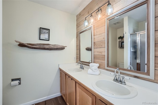 bathroom featuring vanity, a shower with door, wooden walls, wood-type flooring, and toilet