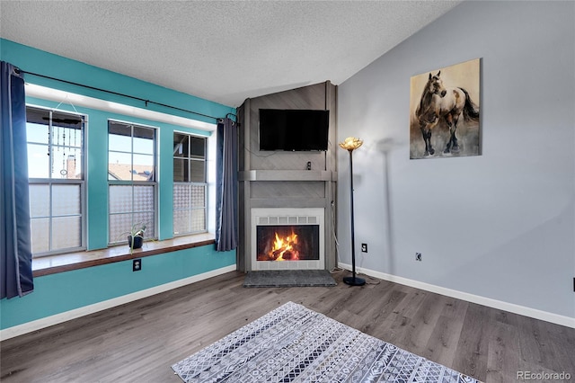 unfurnished living room featuring lofted ceiling, a large fireplace, a textured ceiling, and wood finished floors