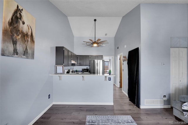 kitchen with a peninsula, wood finished floors, a ceiling fan, baseboards, and freestanding refrigerator