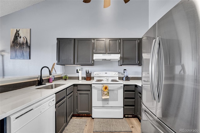 kitchen with white appliances, light countertops, light wood-type flooring, under cabinet range hood, and a sink