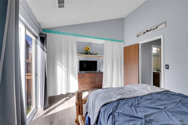 bedroom with visible vents, vaulted ceiling, a textured ceiling, and wood finished floors