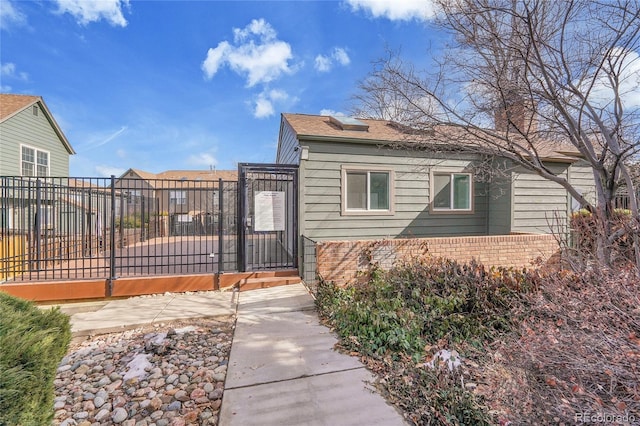 view of property exterior with a gate, fence, and brick siding