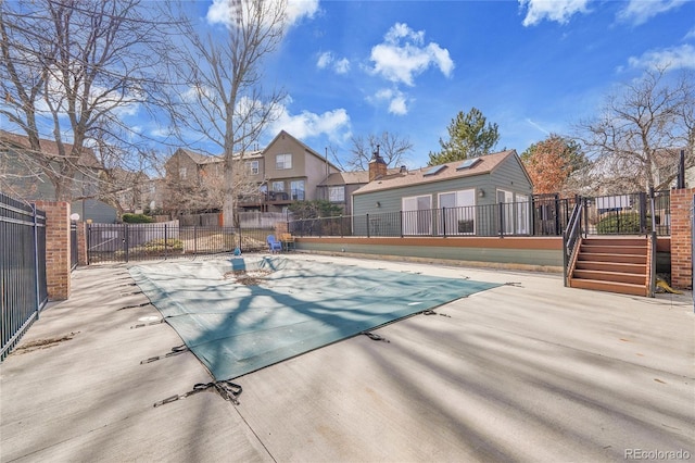 community pool with a patio area, stairs, fence, and a deck