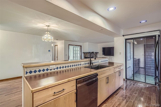 kitchen featuring dishwasher, a sink, light brown cabinets, and wood finished floors