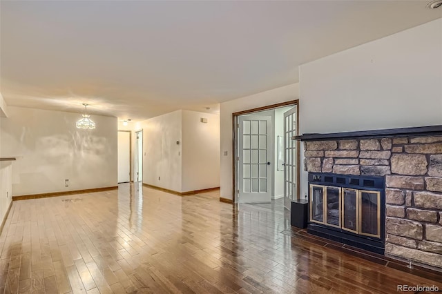 living area featuring a notable chandelier, baseboards, a fireplace, and wood finished floors