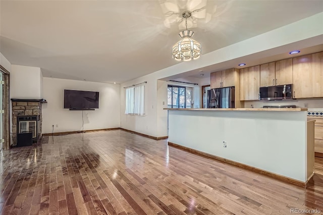 kitchen featuring light countertops, a chandelier, wood finished floors, open floor plan, and stainless steel appliances