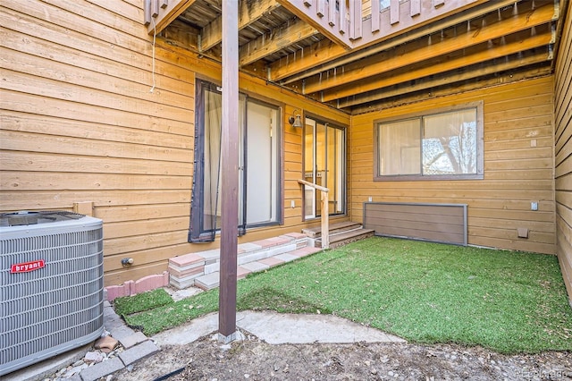 view of exterior entry featuring central AC unit and a yard