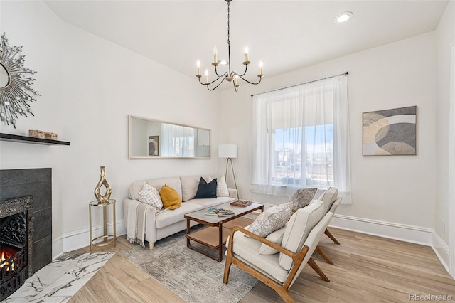 living room featuring a premium fireplace, a chandelier, and light hardwood / wood-style floors