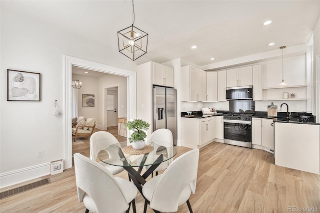 dining room with sink, a chandelier, and light wood-type flooring