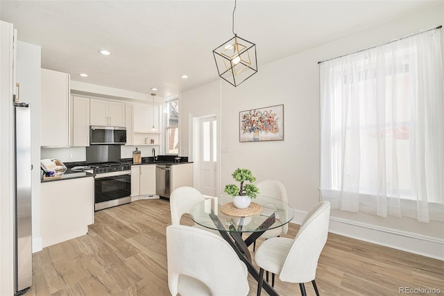 dining space with light hardwood / wood-style floors and a chandelier