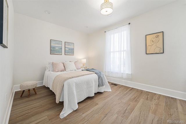 bedroom featuring multiple windows and light hardwood / wood-style flooring