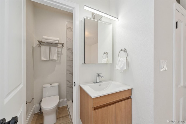 bathroom with hardwood / wood-style flooring, toilet, and vanity