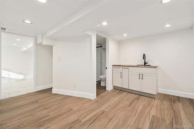 bar with light hardwood / wood-style floors, sink, and white cabinets