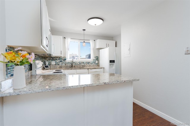 kitchen featuring light stone countertops, baseboards, white appliances, a sink, and a peninsula