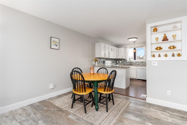 dining space with light wood-type flooring and baseboards