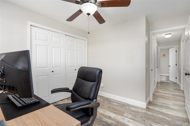 office space with baseboards, a ceiling fan, and light wood-style floors