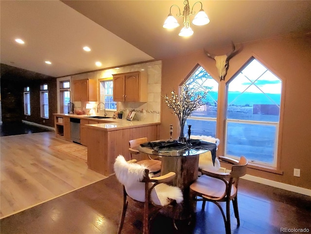 dining space with sink, light hardwood / wood-style flooring, and a notable chandelier