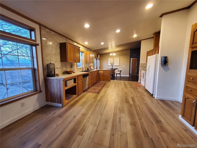 kitchen with dishwasher, sink, kitchen peninsula, white fridge, and light wood-type flooring