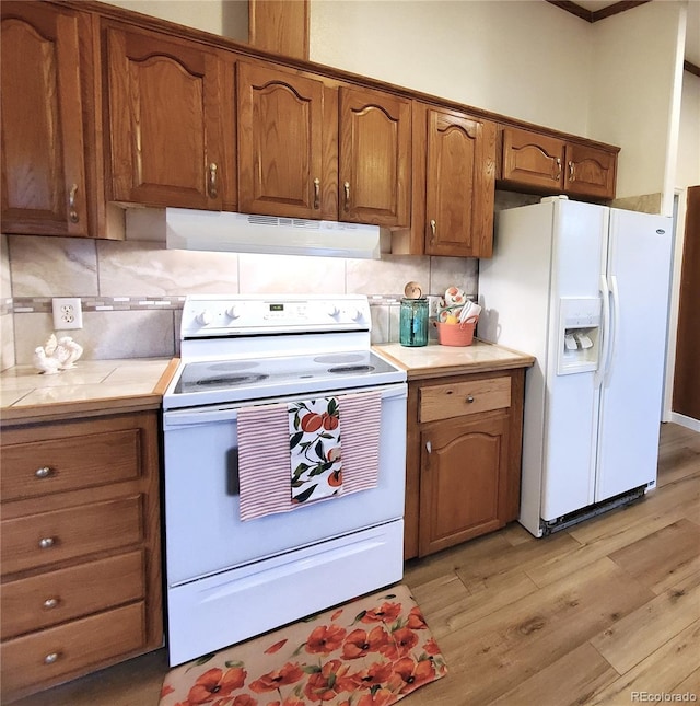 kitchen with decorative backsplash, white appliances, and light hardwood / wood-style flooring