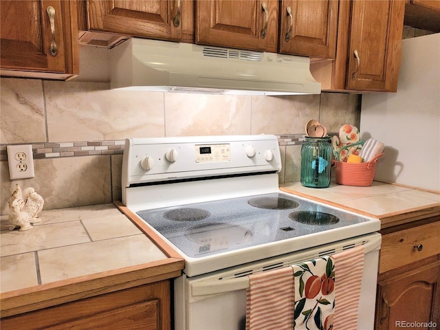 kitchen featuring backsplash, white range with electric cooktop, and tile counters