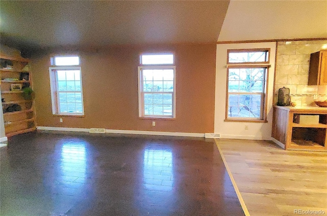 unfurnished living room featuring plenty of natural light and hardwood / wood-style flooring